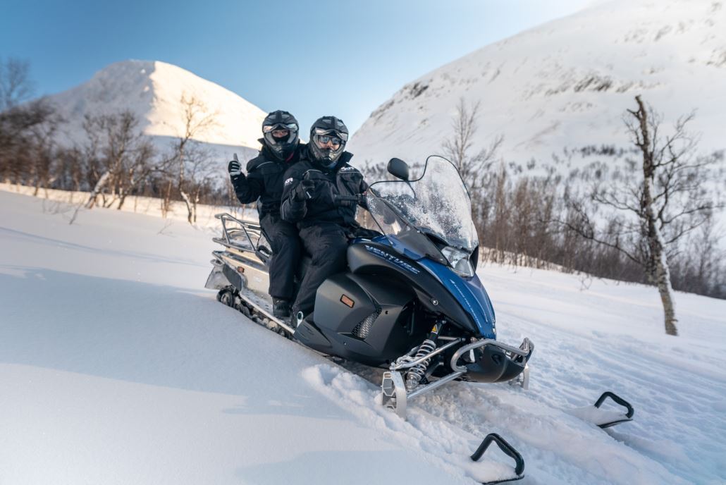 to people driving a snowmobile in Tromsø